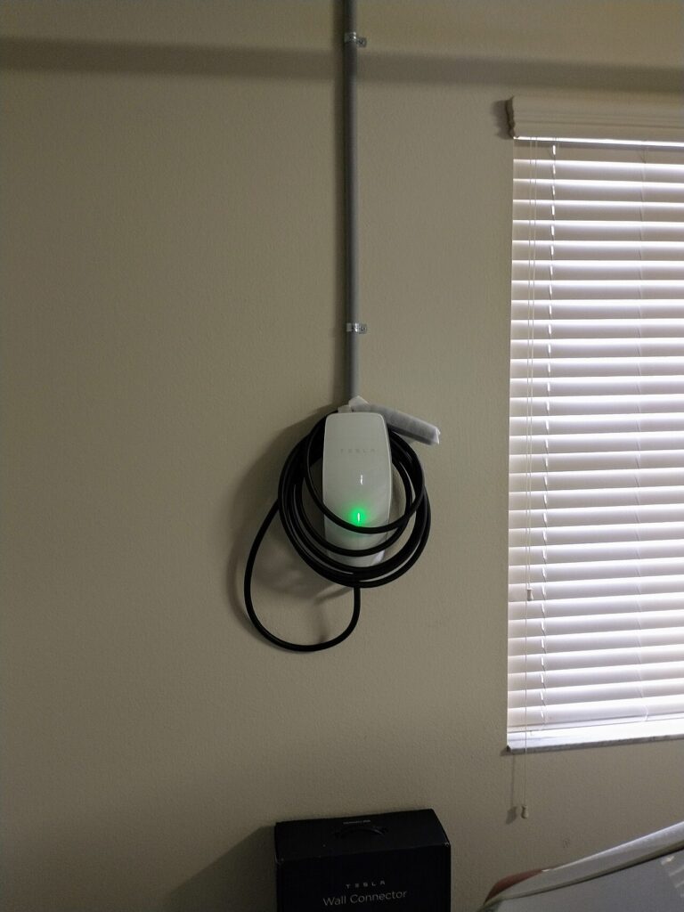 Tesla Wall Connector home charger mounted on a garage wall
