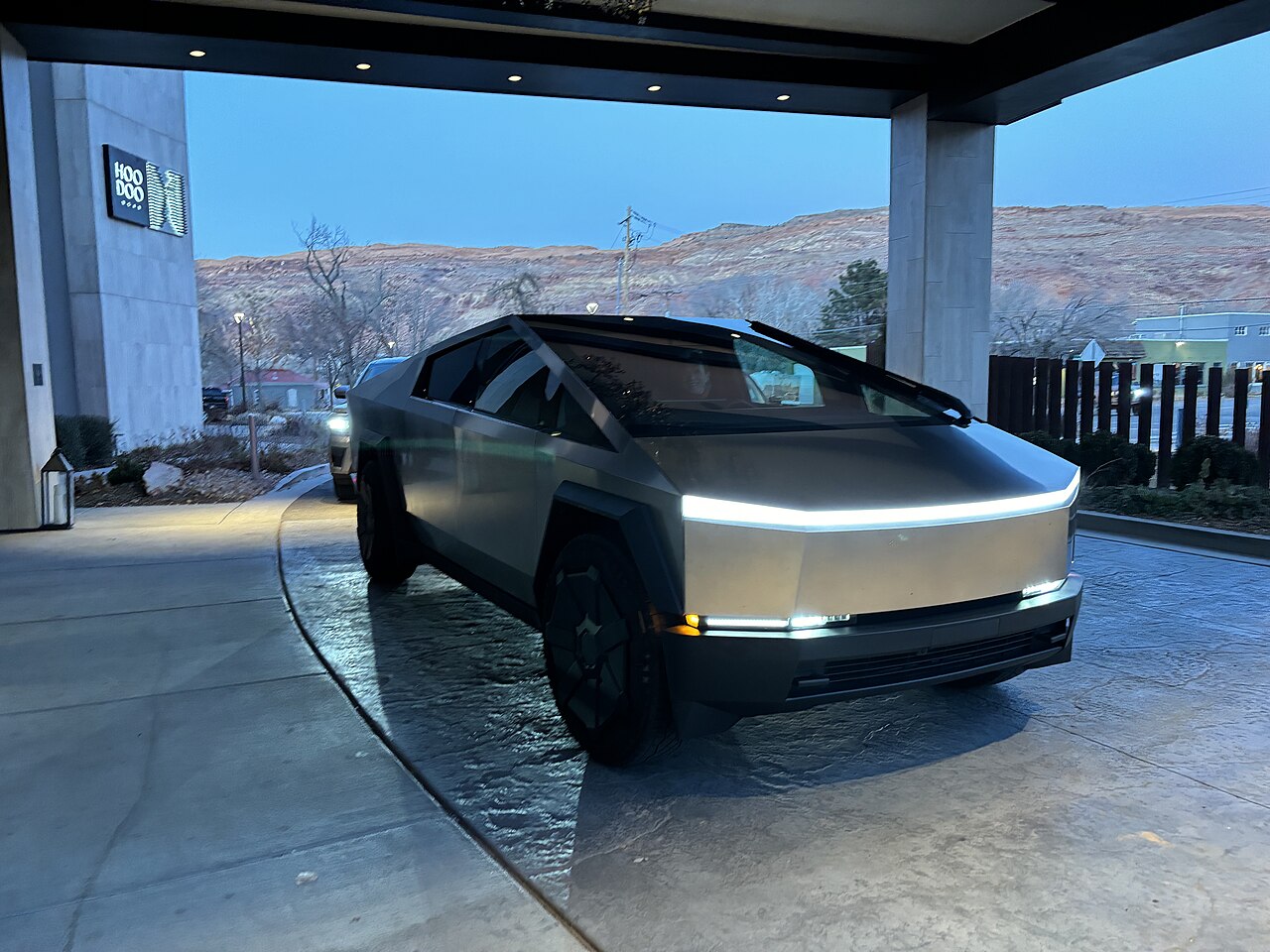 Tesla Cybertruck parked off-road in Moab, Utah, showing its stainless steel body and truck bed