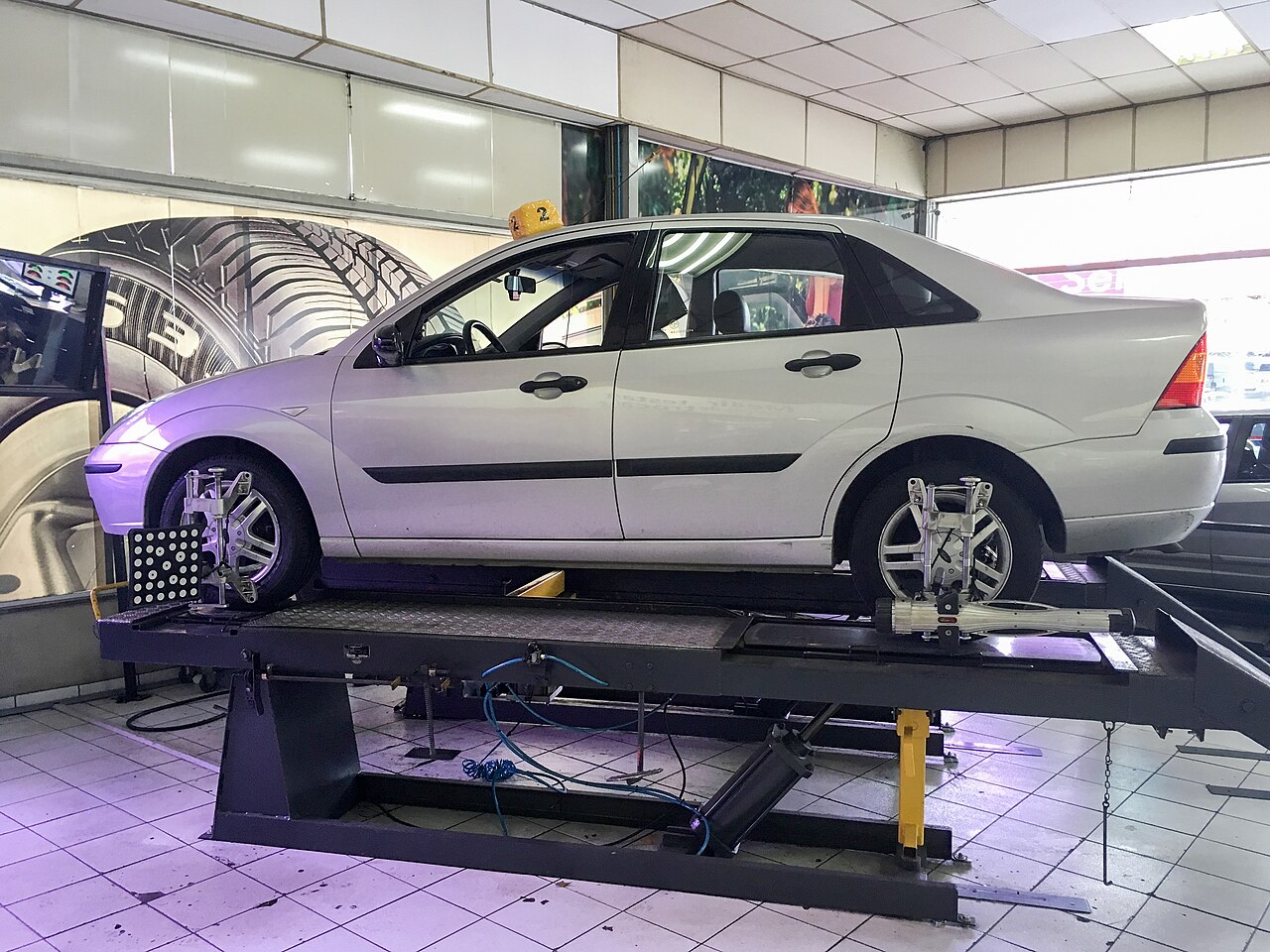 轮胎店举升台上正在做四轮定位的汽车,轮毂上装有定位仪靶标