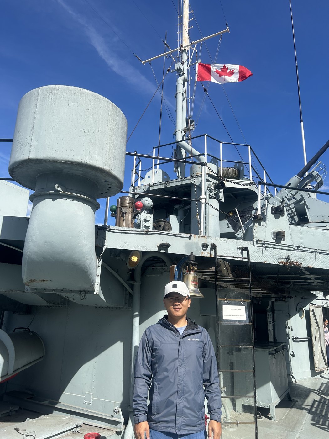 Lifei Zhou, author of Tesla North America Guide (tslna.com), standing on the deck of a warship with the Canadian flag in the background
