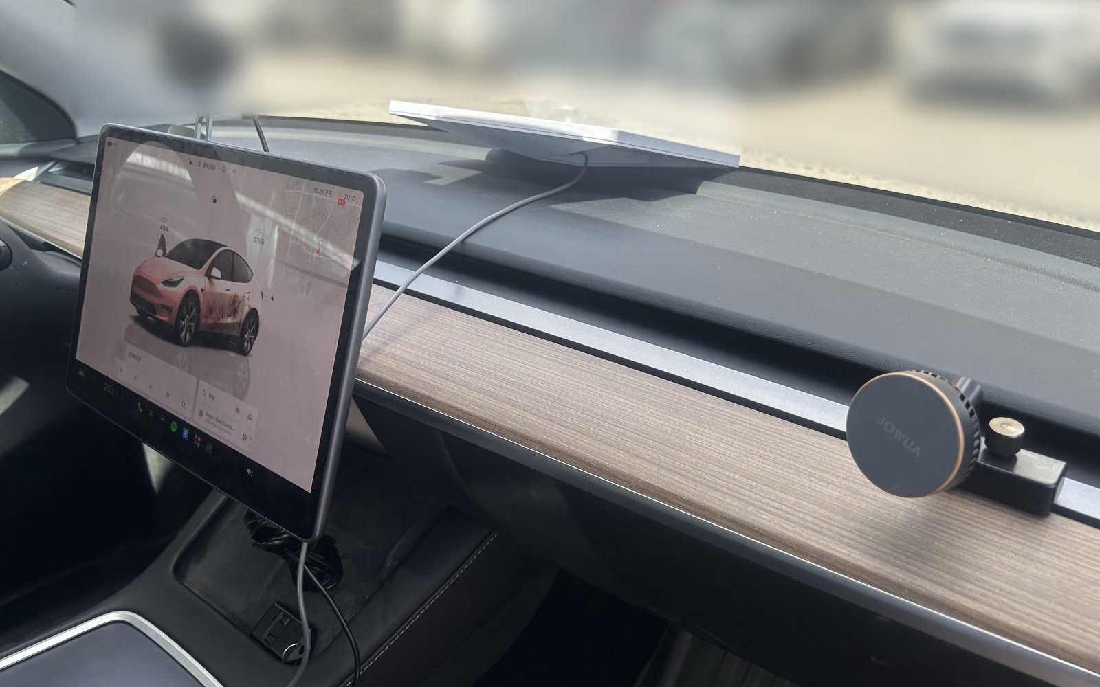 Starlink Mini lying flat on a Tesla Model Y dashboard below the windshield, with the power cable running down beside the centre screen
