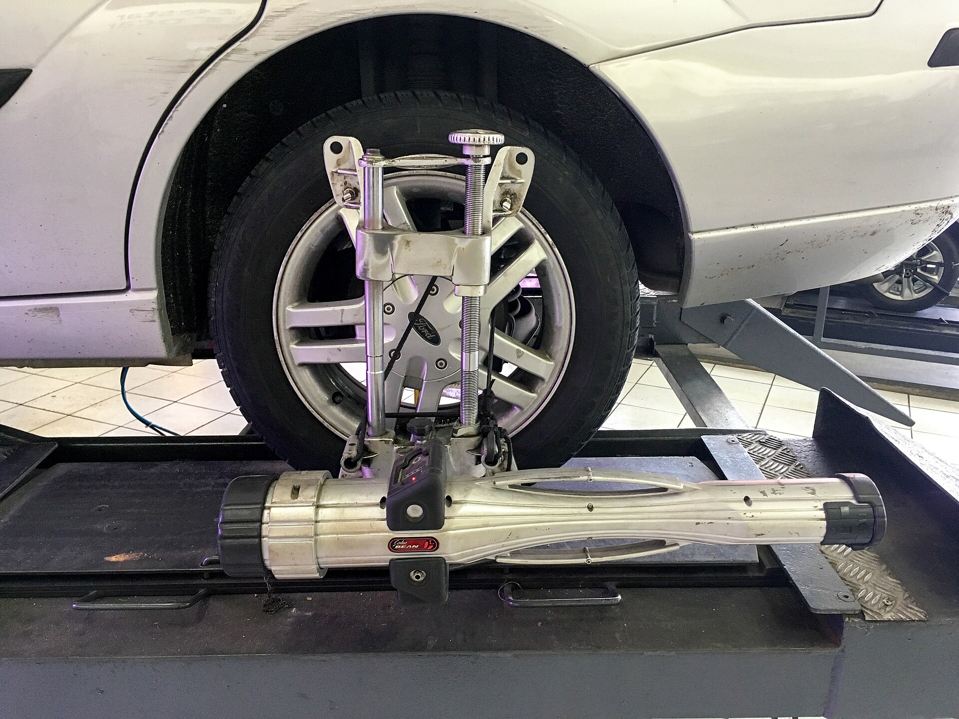 Wheel alignment sensor clamped to a car wheel on an alignment rack